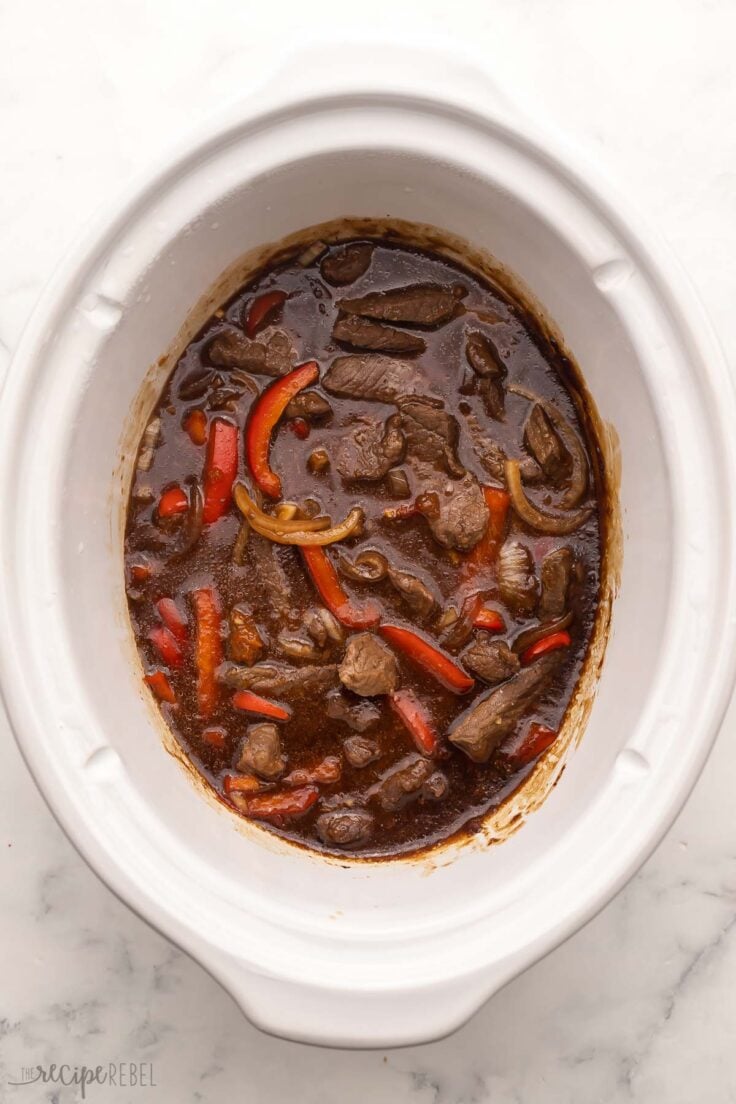 white slow cooker filled with cooked mongolian beef.