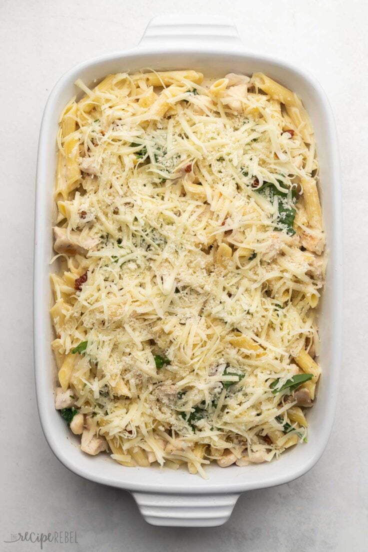 white baking dish filled with pasta and sauce, topped with shredded cheese.