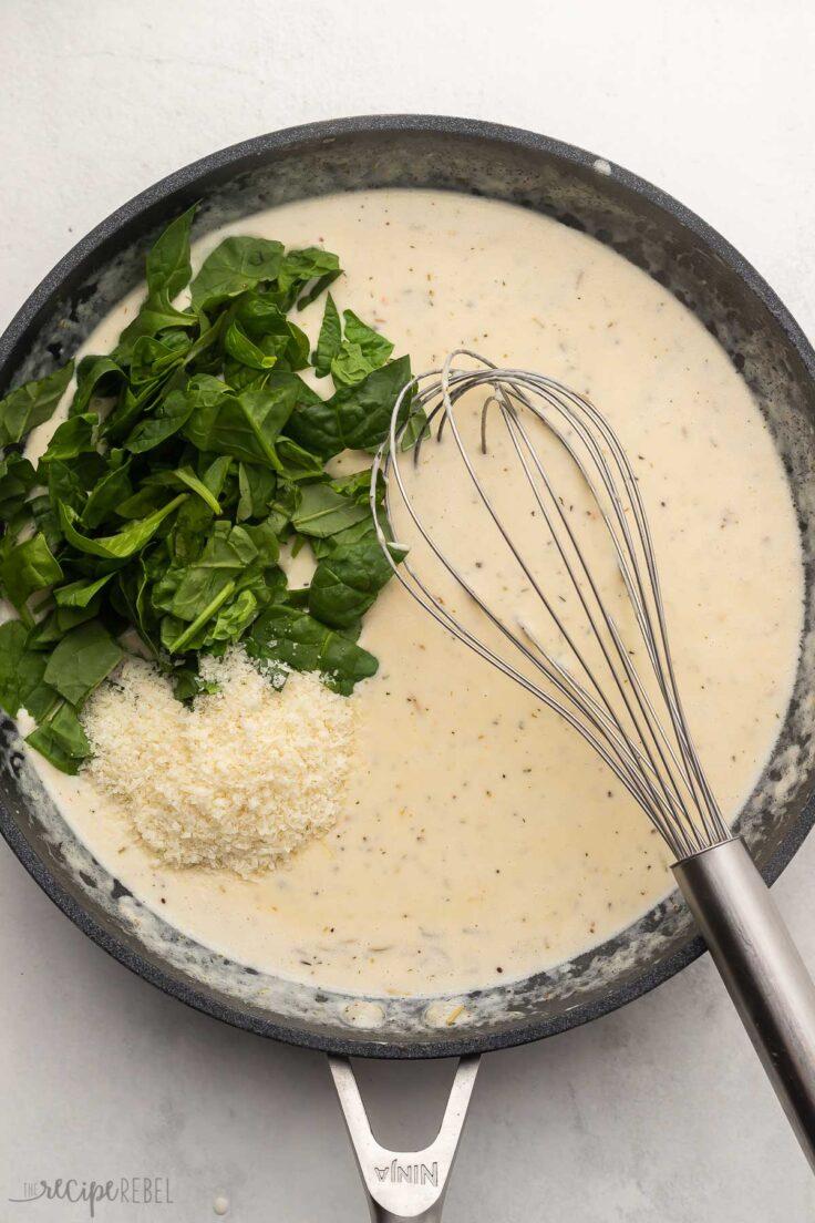 chopped spinach and cheese added to sauce in black frying pan.