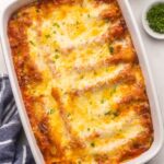 close up view of baked cheese cannelloni in dish topped with chopped parsley.