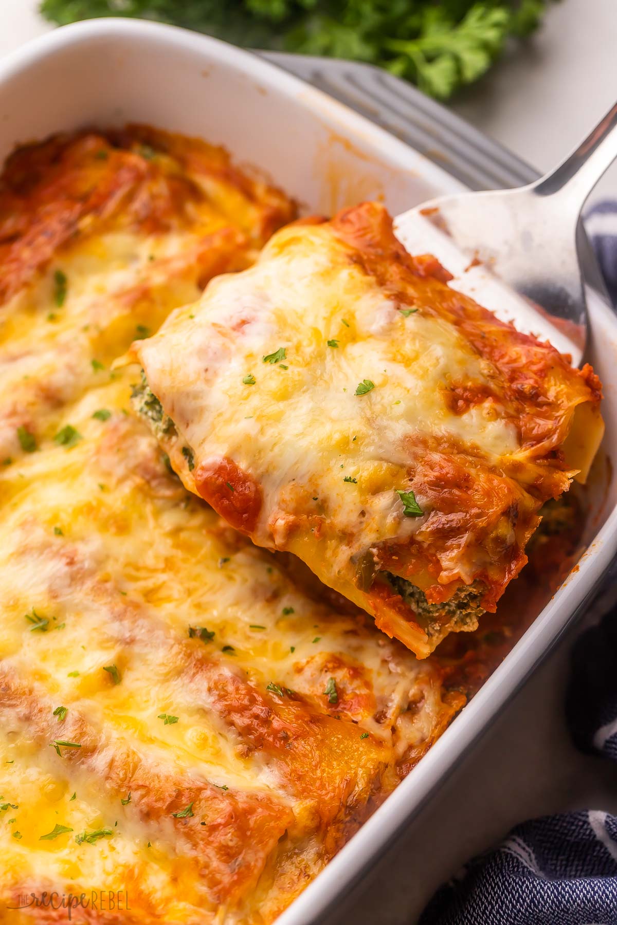 a piece of three cheese cannelloni being scooped out of baking dish.