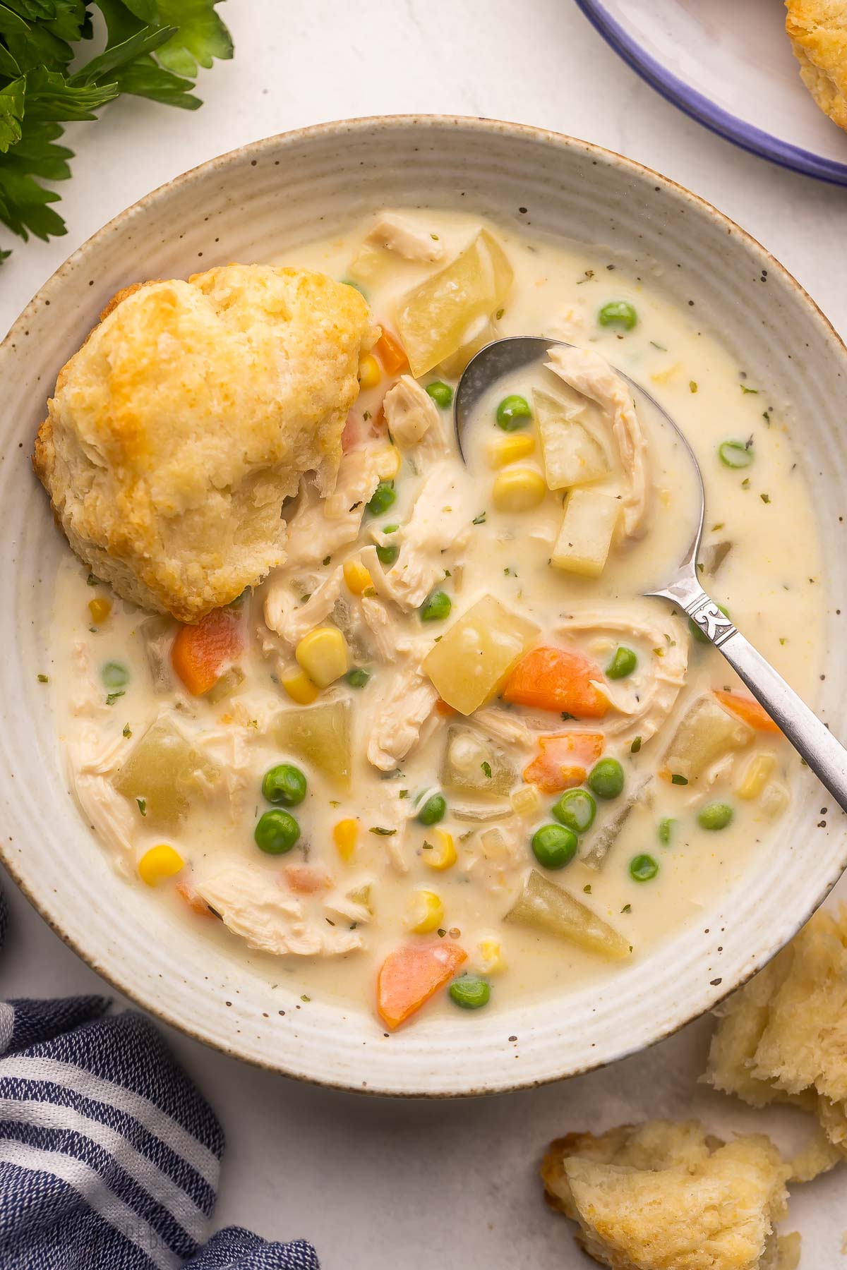 bowl of chicken pot pie soup with spoon and biscuit on the side.