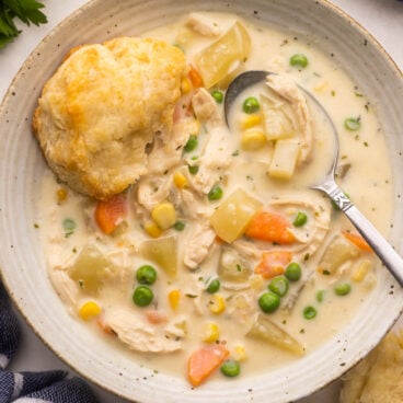close up of a bowl of chicken pot pie soup with a biscuit on the edge.