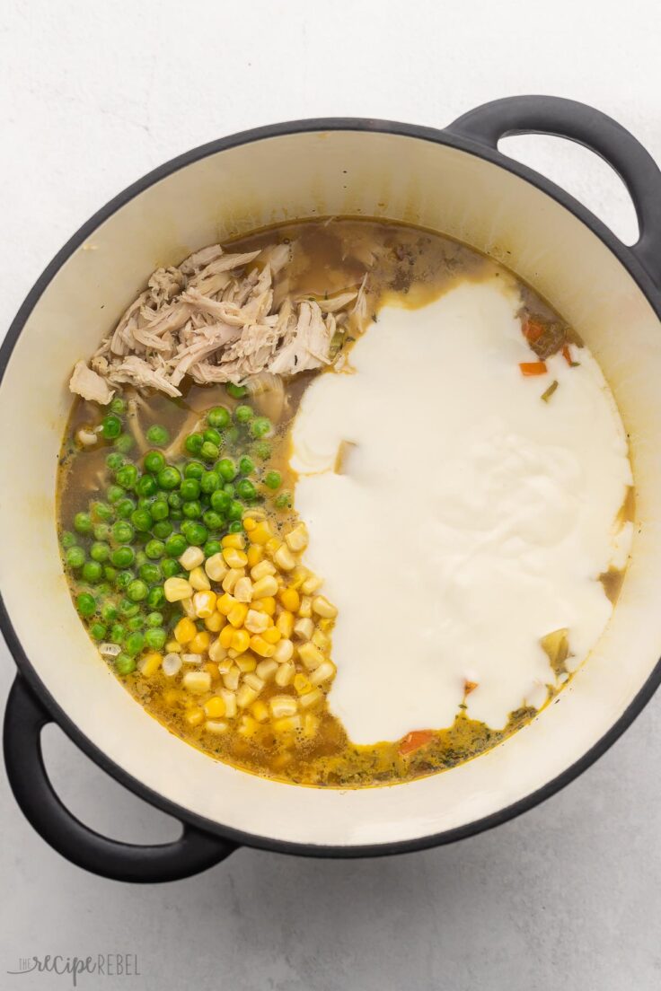 large pot with frozen vegetables and white sauce added.