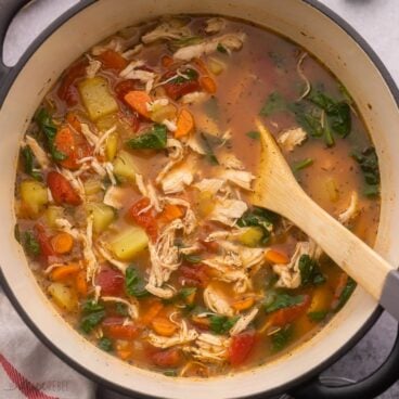 close up of chicken vegetable soup in large black pot.
