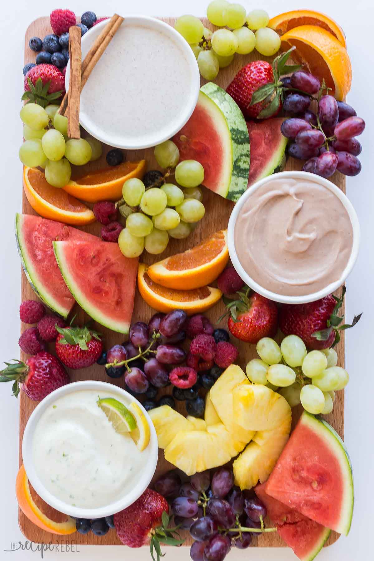 variety of fruit dip flavors on a board with fruit.