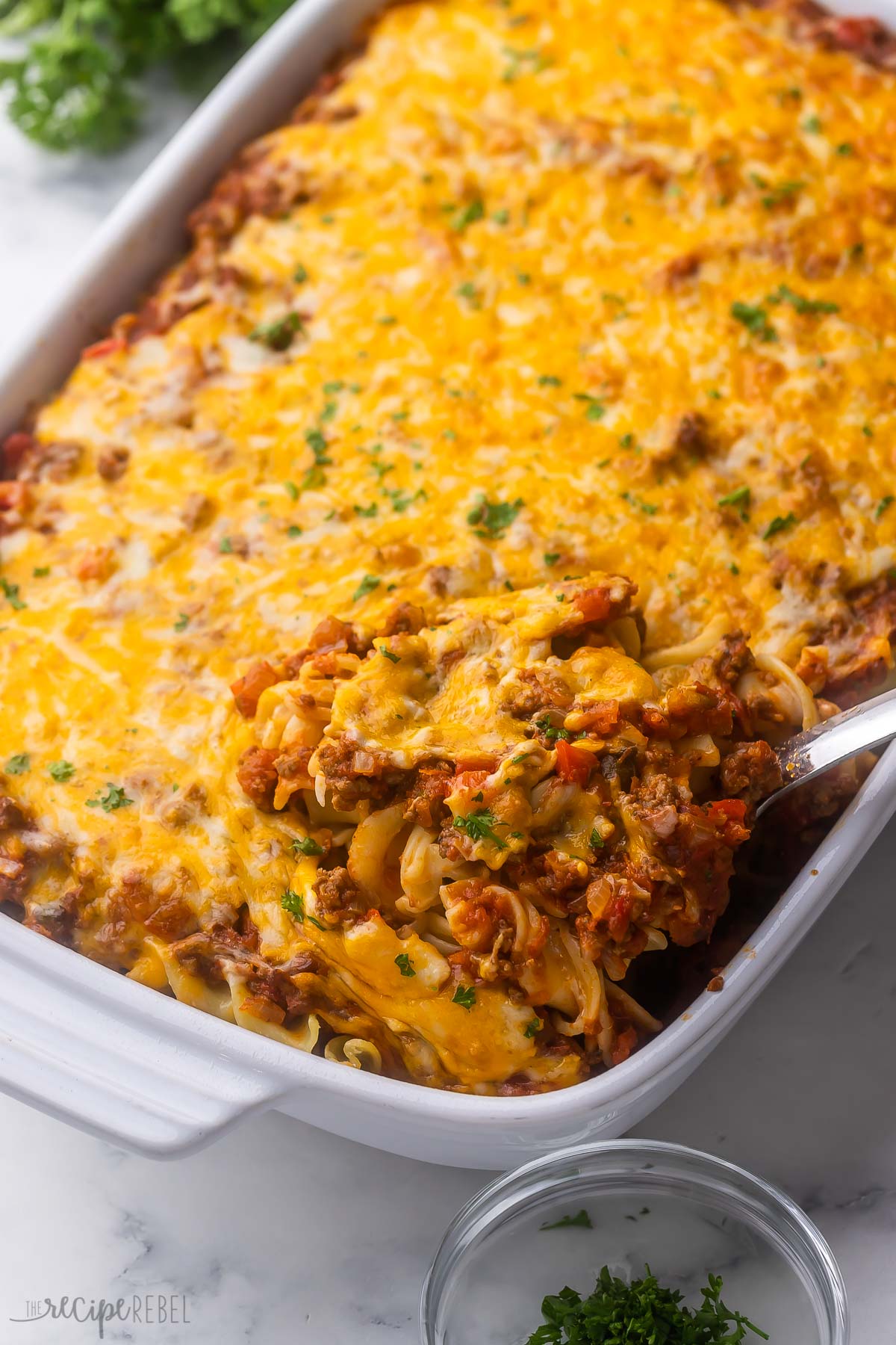 baked beef casserole being scooped out of dish.