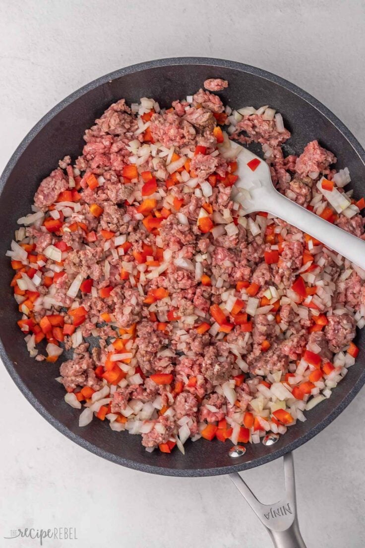 ground beef and chopped vegetables cooking in black pan.