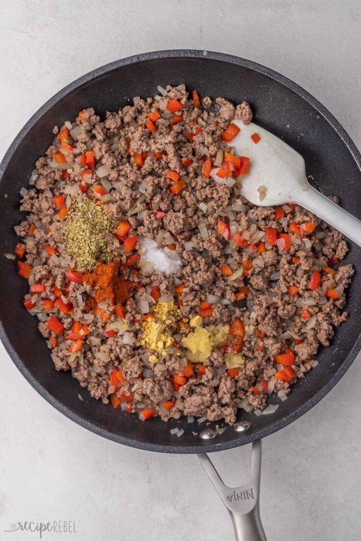 cooked ground beef and spices in black frying pan.