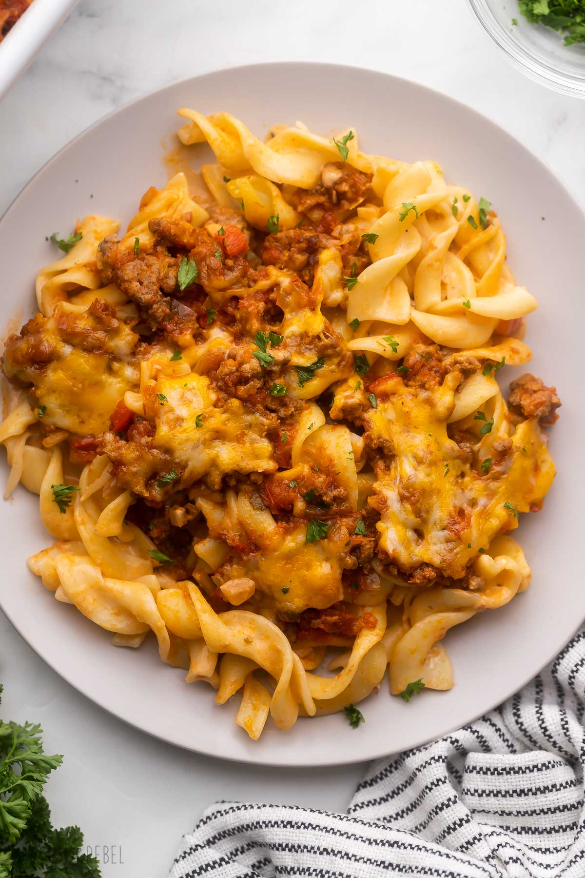 grey plate full of ground beef casserole with parsley beside.