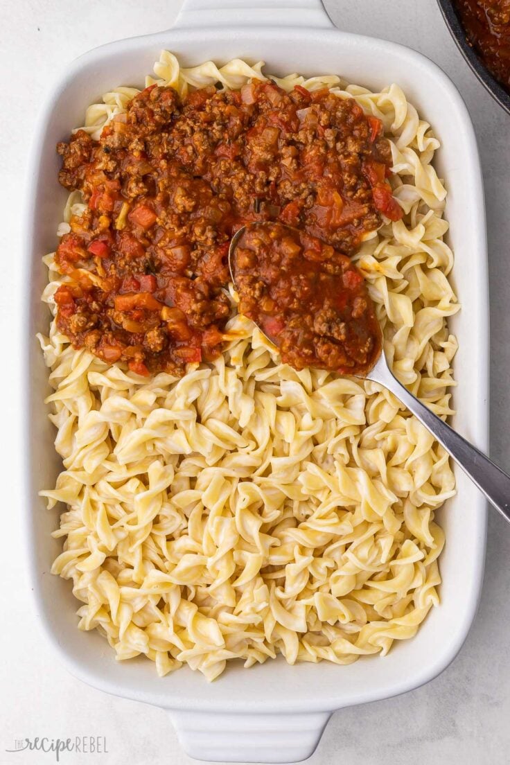 pasta in white baking dish with ground beef sauce added to top.