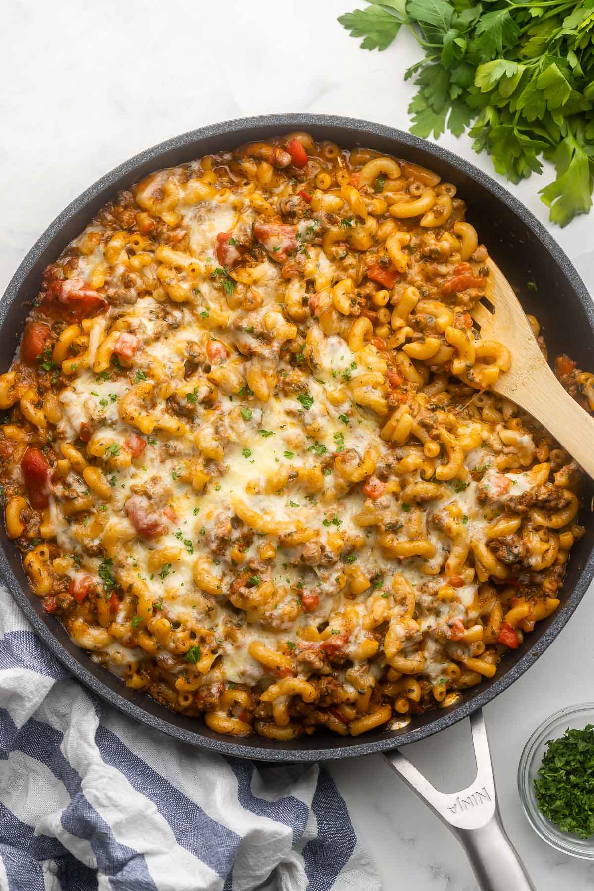 black pan filled with homemade hamburger helper on grey surface with parsley beside.