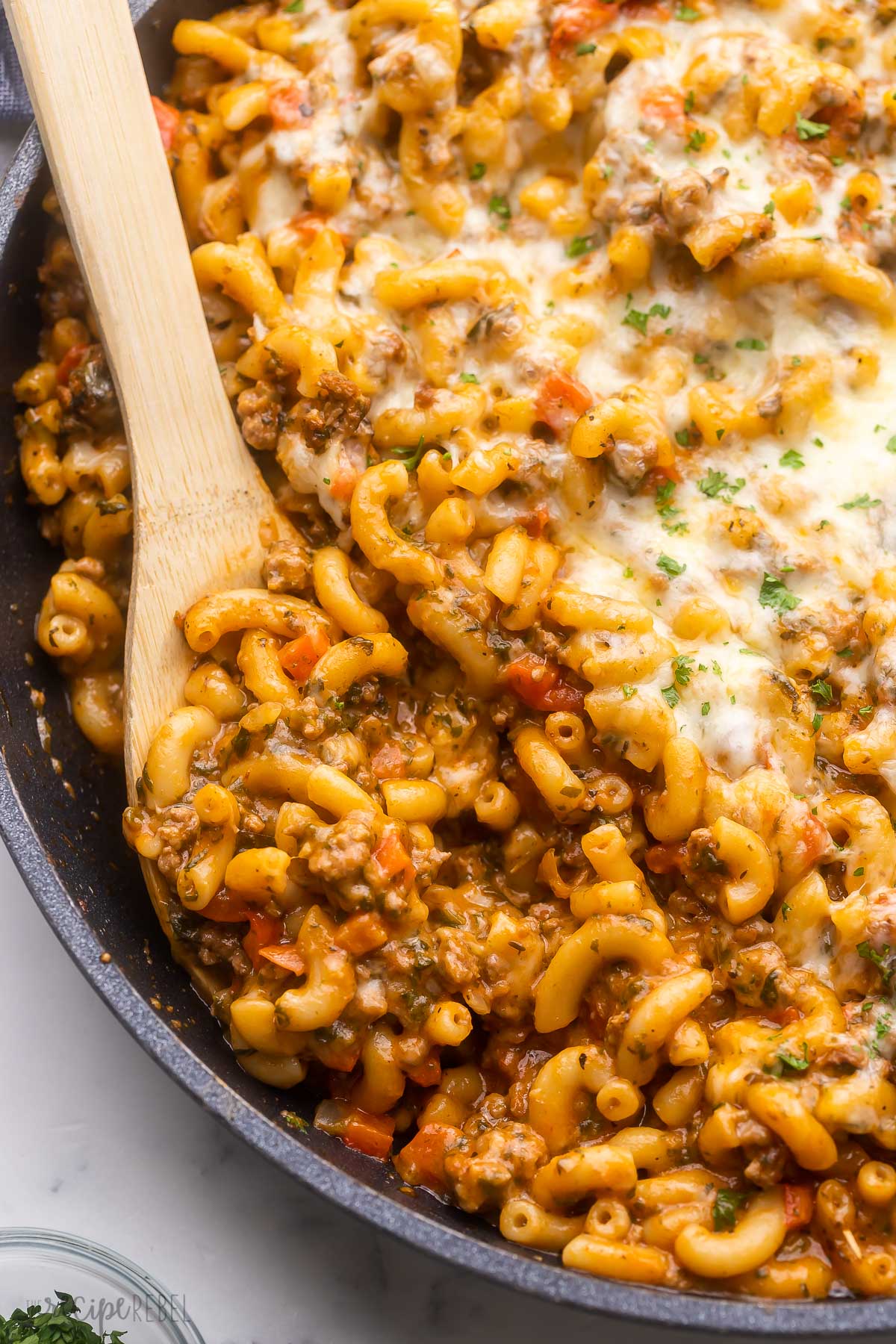 black pan filled with homemade hamburger helper and a wooden ladle in it.