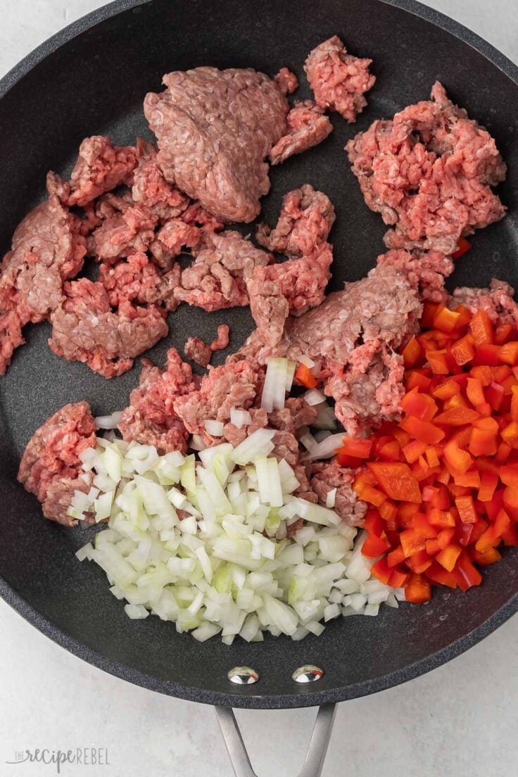 ground beef, onions and red peppers in black pan to be cooked.
