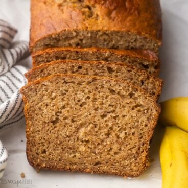 sliced banana bread loaf with bananas beside.