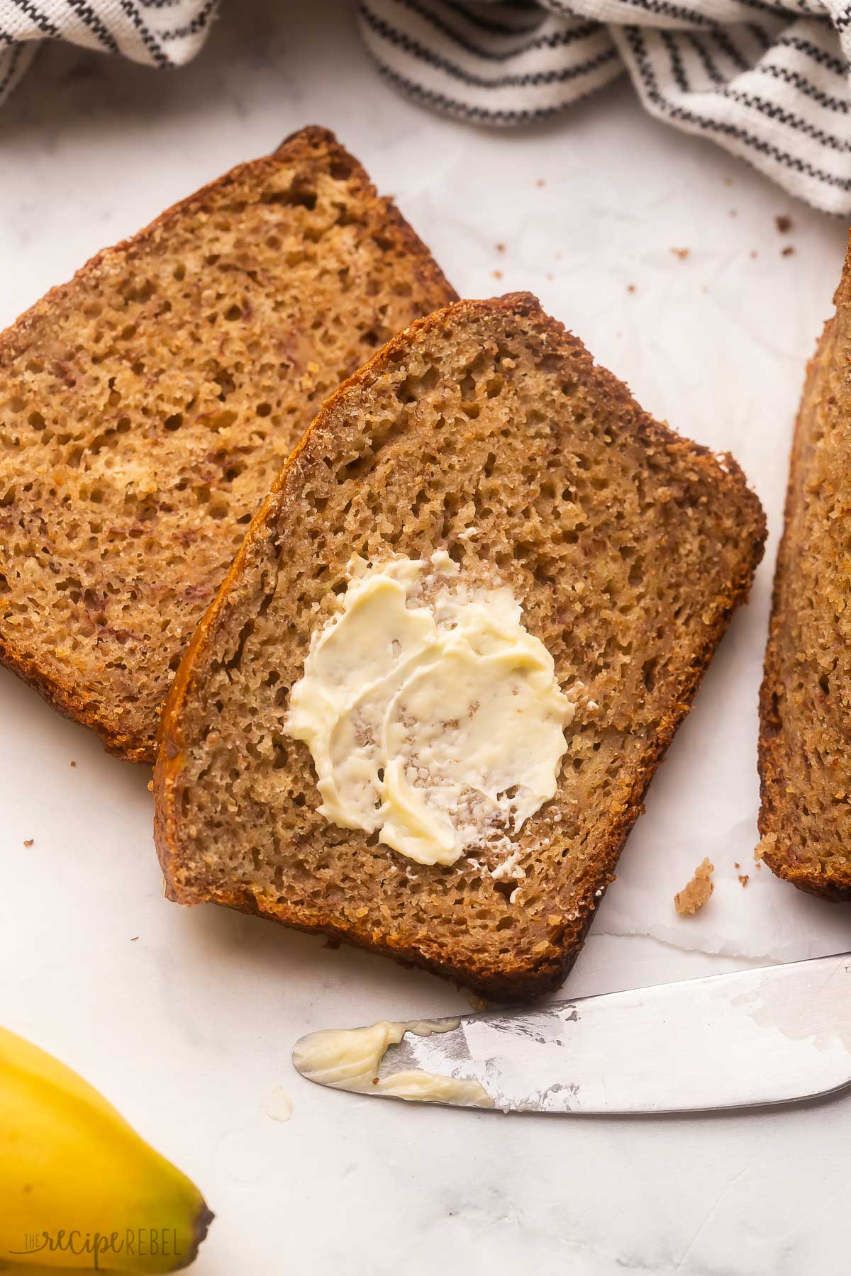 sliced banana bread with butter on a grey surface.