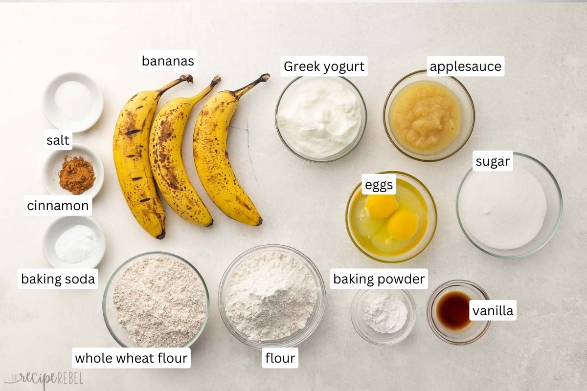 ingredients needed for healthy banana bread in glass bowls on grey surface.