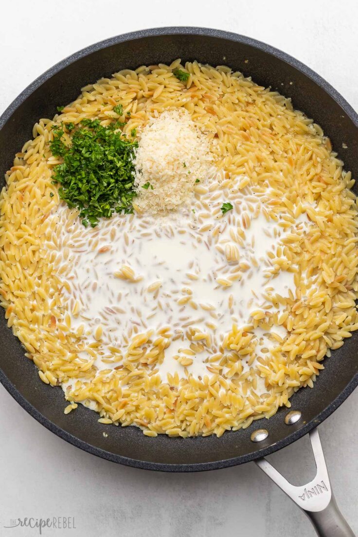 cooked orzo in pan with cream, cheese and parsley added to top.