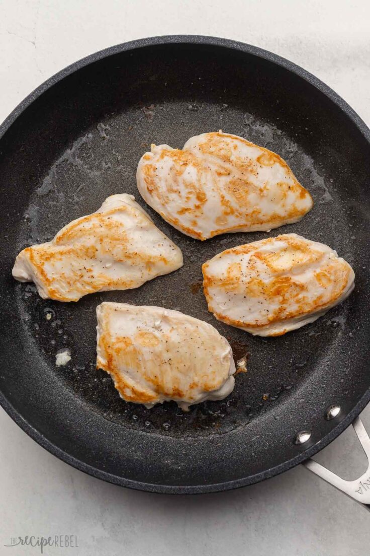 black pan with four cooked chicken breasts.