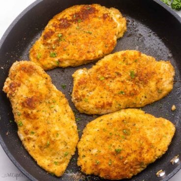 close up of cooked chicken breasts in black frying pan.