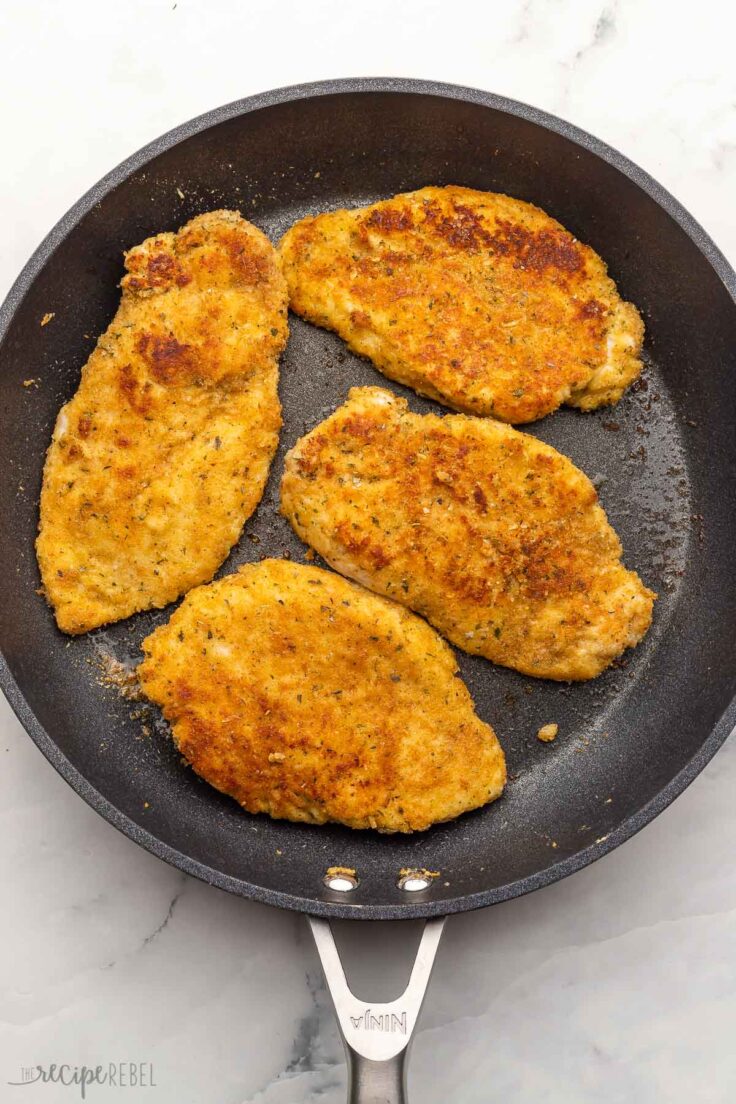 large black pan with four cooked chicken breasts.