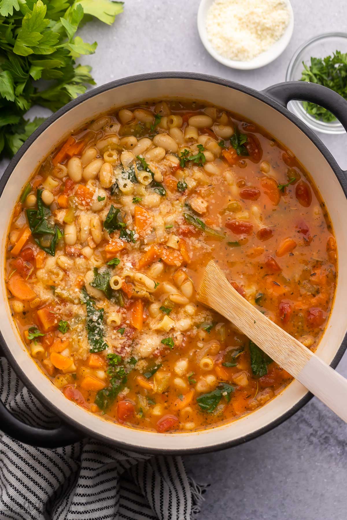 black pot full of pasta fagioli with wooden ladle in it.