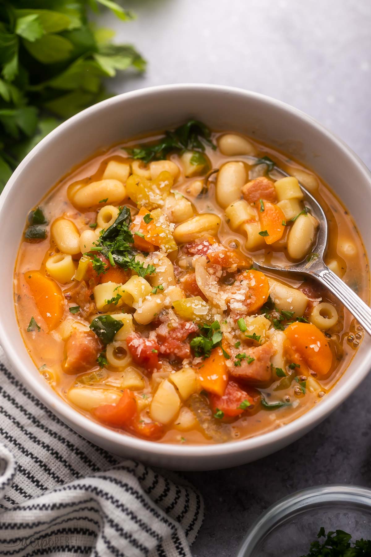 grey bowl filled with patsa fagioli and topped with chopped parsley.