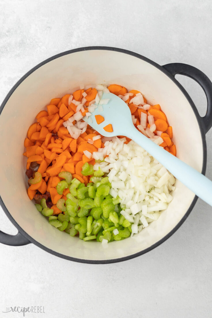 large pot filled with chopped vegetables and blue spatula.