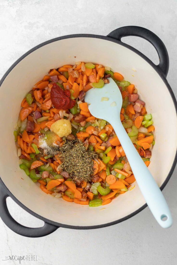 sauteed vegetables in large pot with spices added on top.