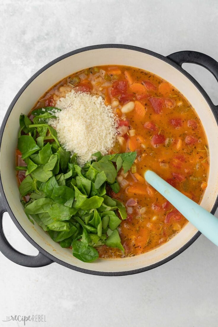 spinach and parmesan added to large pot of pasta fagioli.
