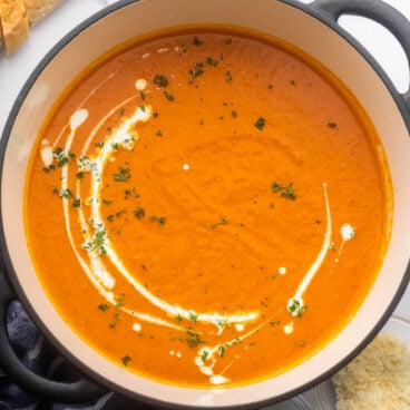 square image of roasted red pepper soup in black dutch oven.