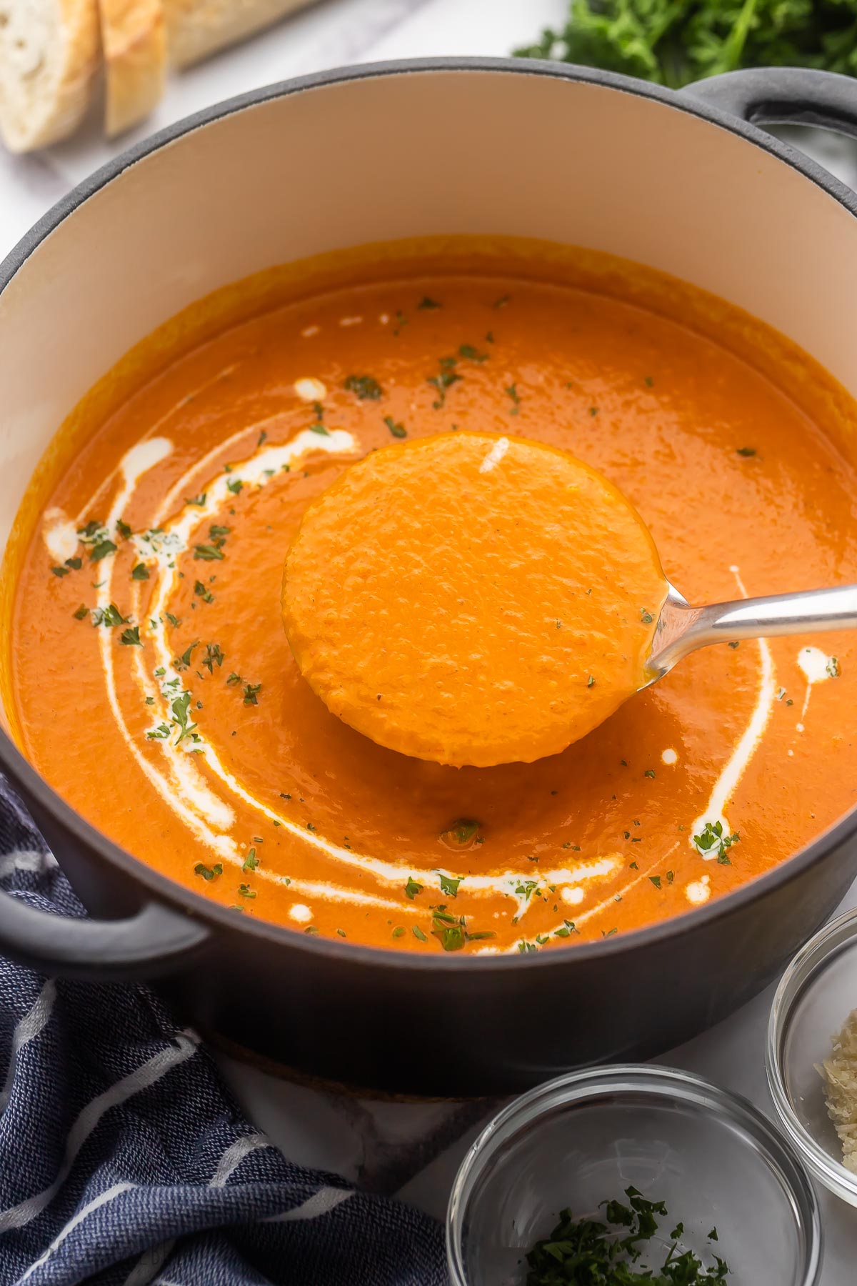 close up image of metal ladle in roasted red pepper soup.