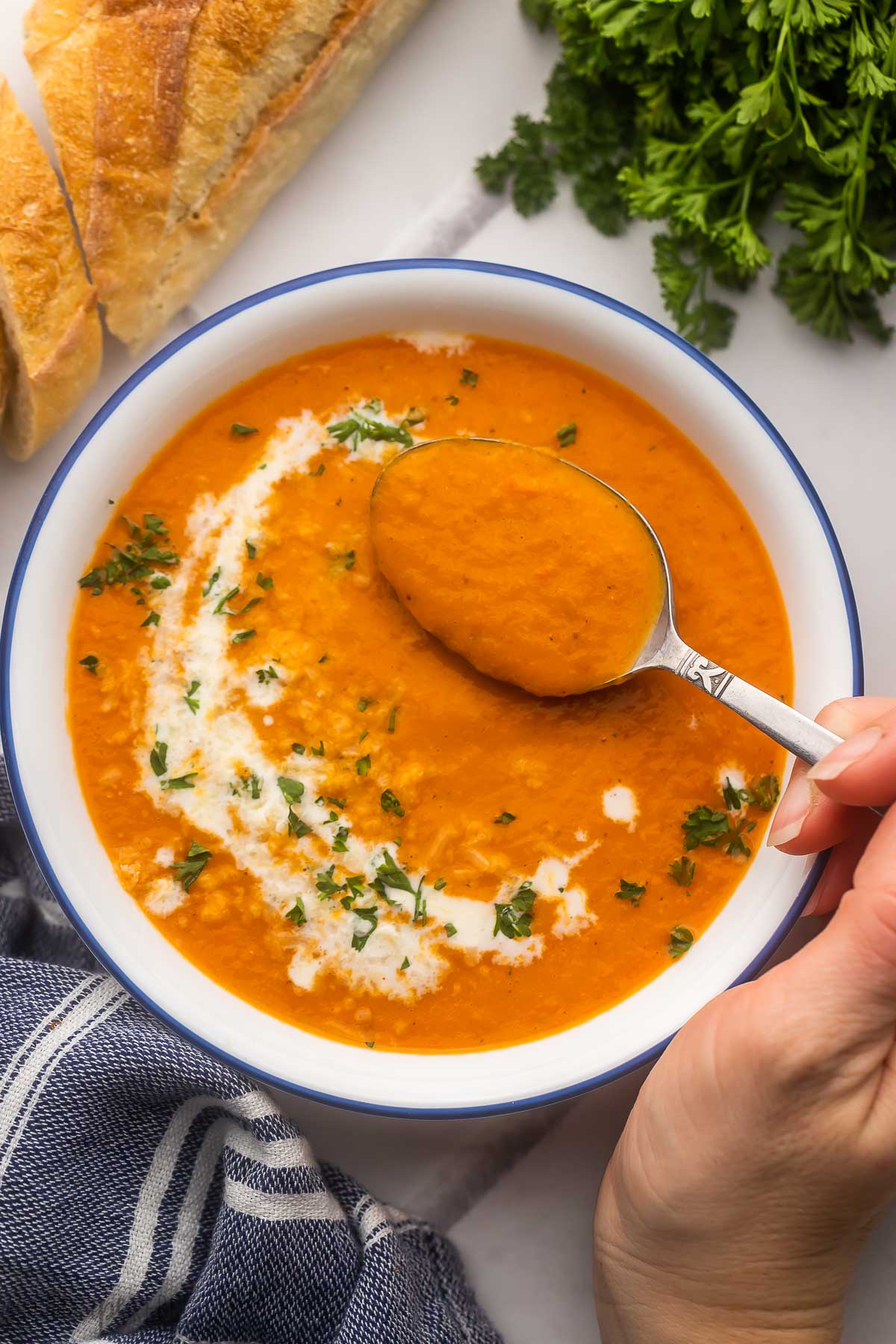 overhead image of bowl of roasted red pepper soup with spoon stuck in.