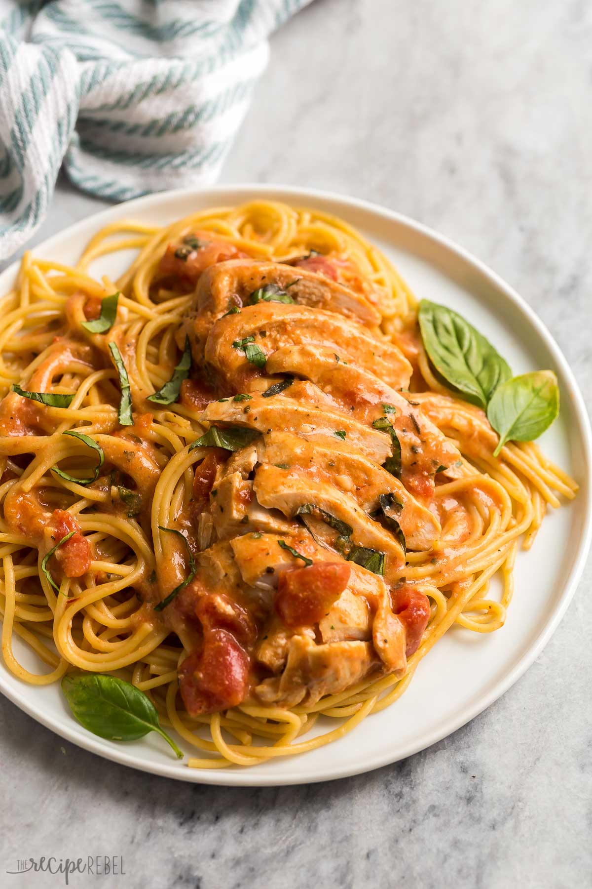 close up image of slow cooker chicken breasts over spaghetti. 