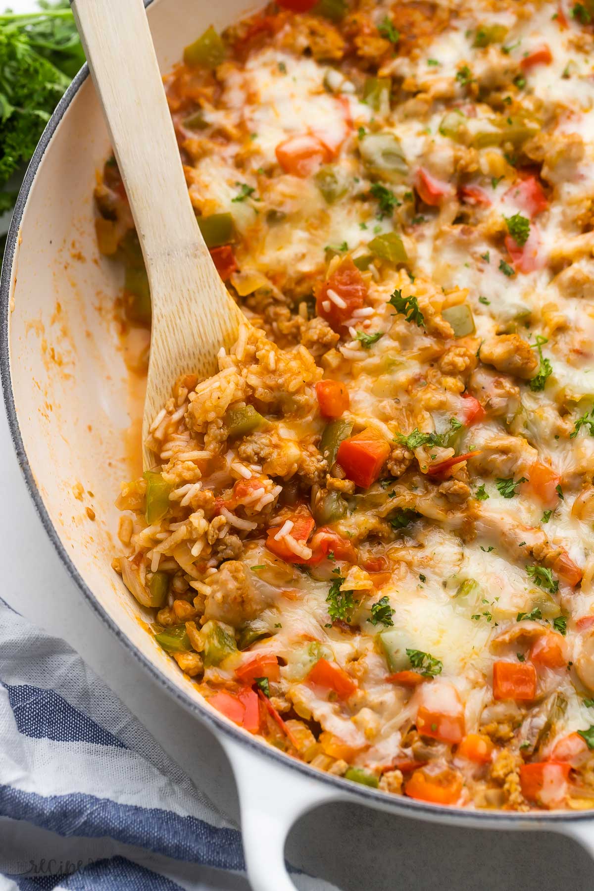 wooden ladle scooping stuffed pepper casserole out of white dish.