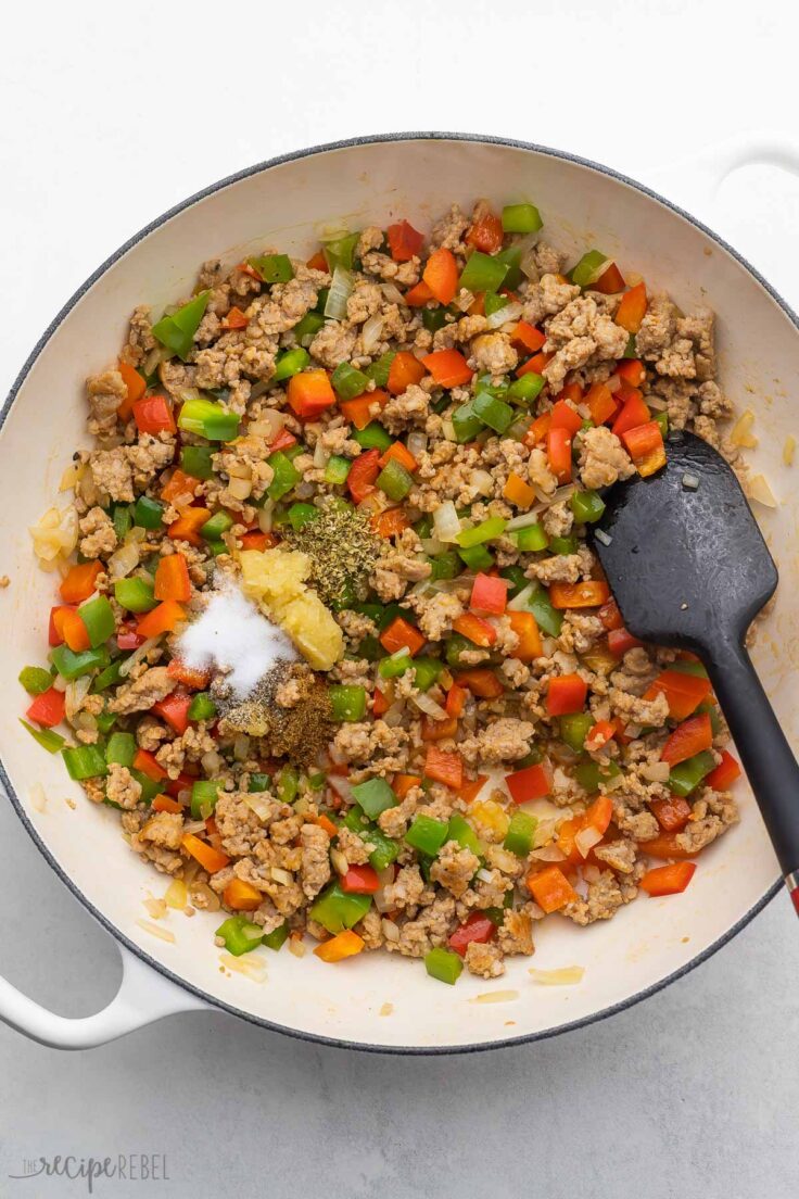 pan filled with sauteed vegetables, meat and spices added on top.