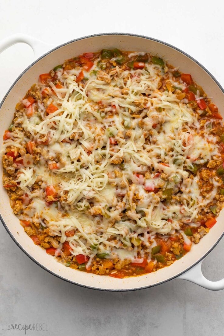 large white pan of stuffed pepper casserole with shredded cheese added to top.
