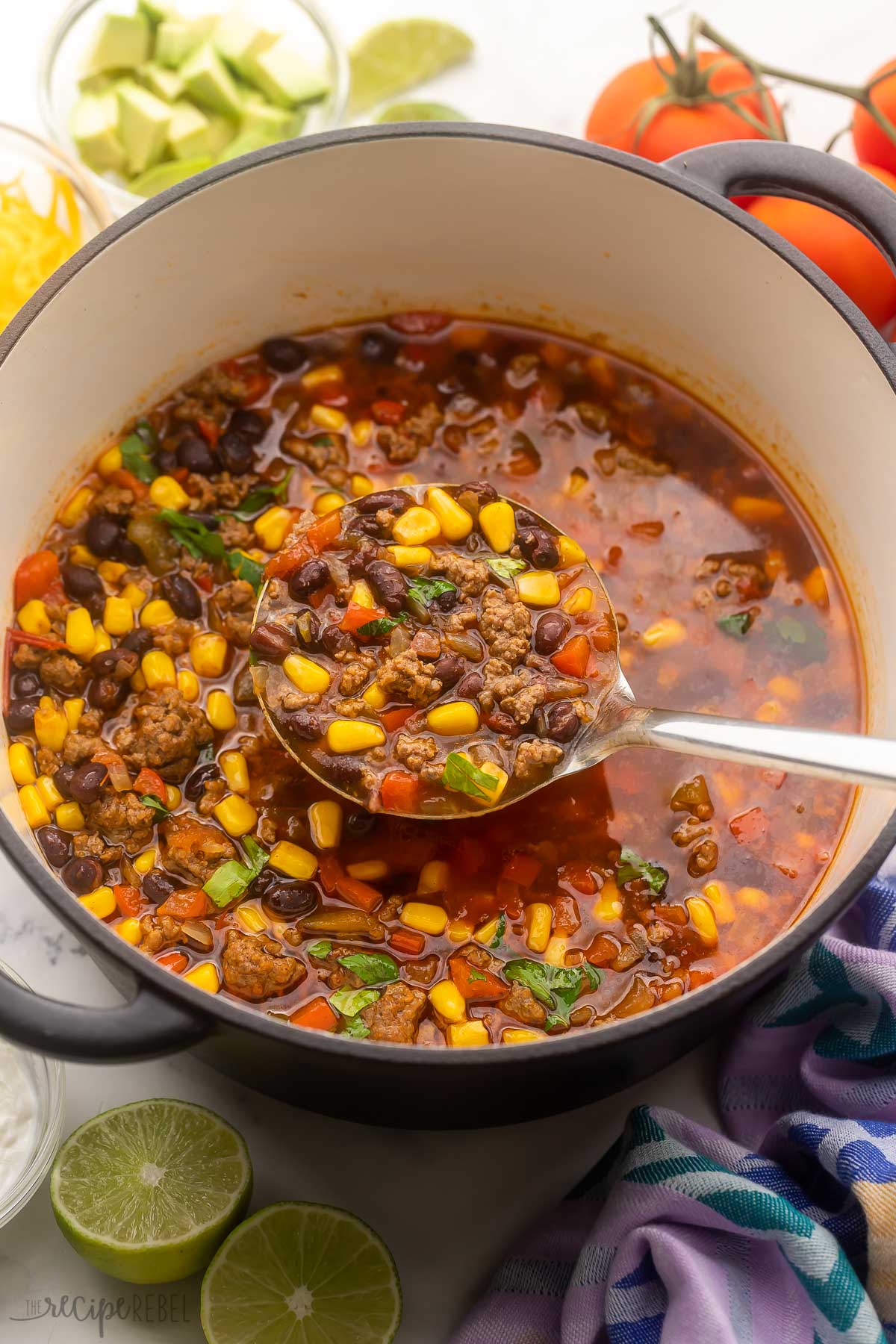 a full scoop of taco soup being scooped out of pot with toppings nearby.