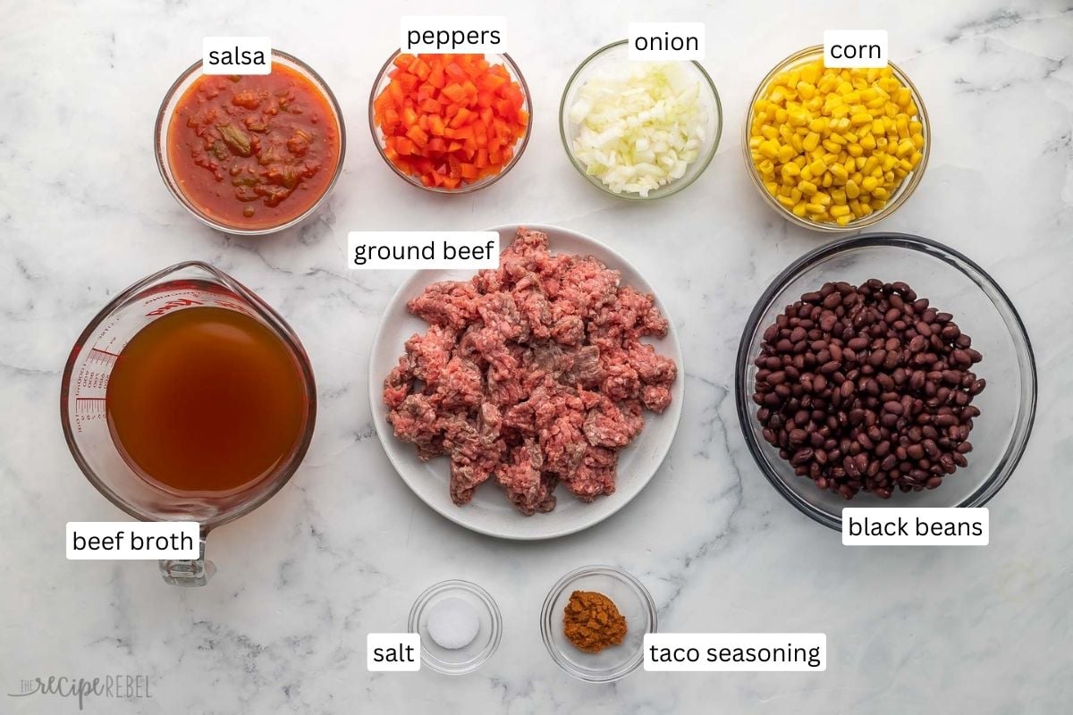 ingredients needed for taco soup in glass bowls on grey surface.