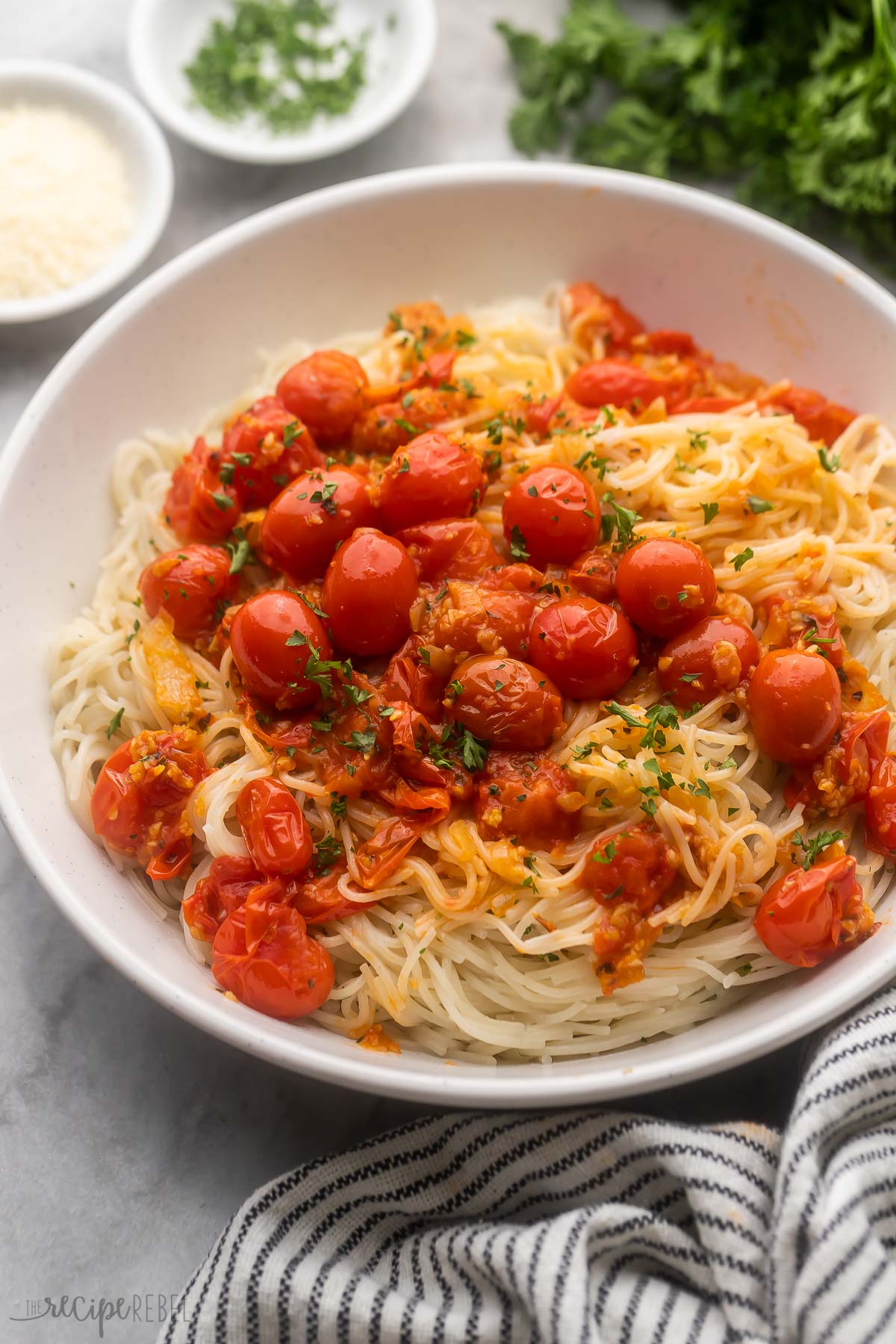 plate full angel hair with tomatoes and chopped parsley on top.