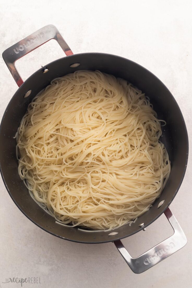 large pot with cooked angel hair pasta on grey surface.