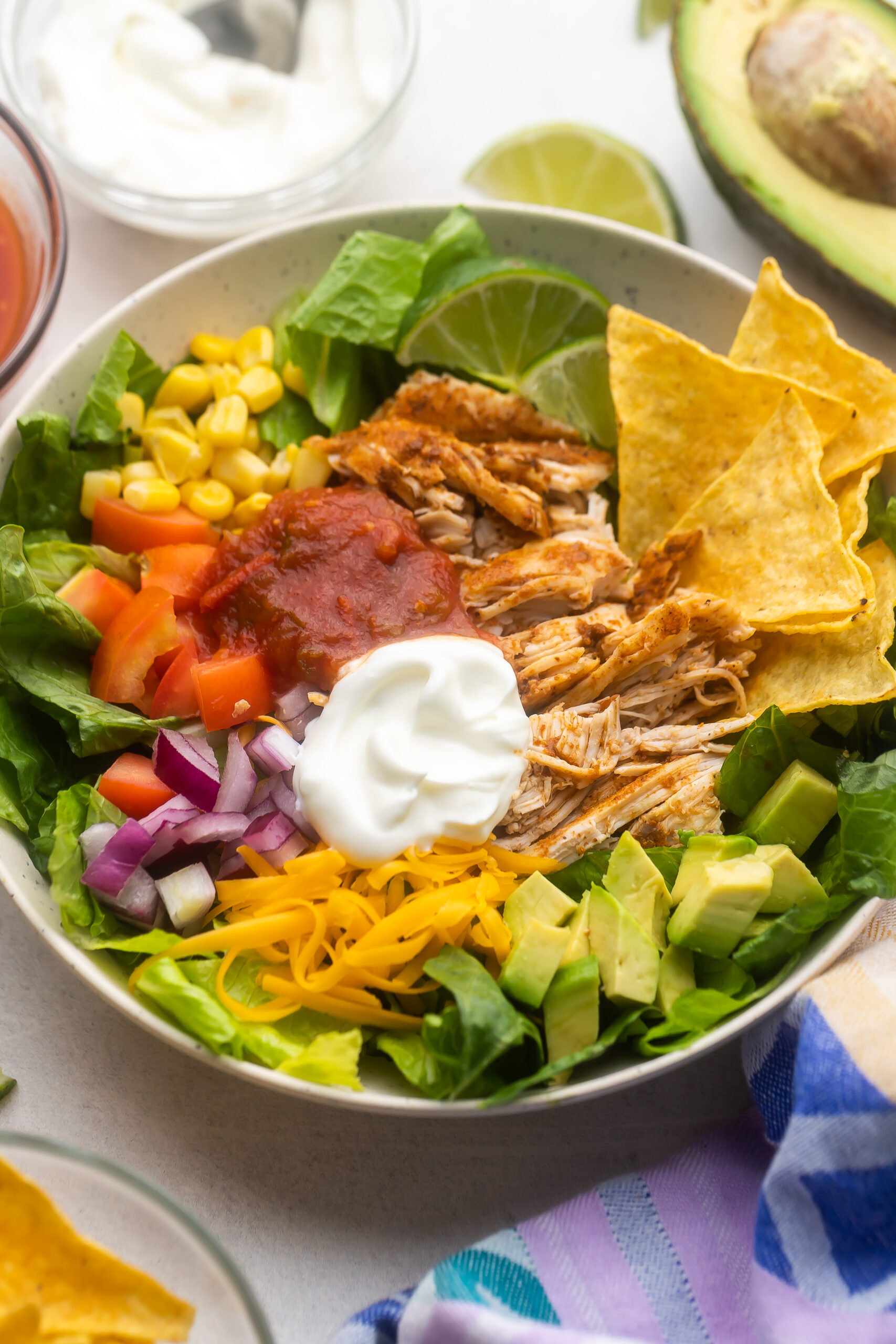 large bowl of taco salad with sour cream and salsa on top.