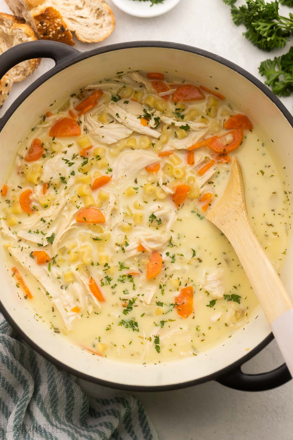 large pot with creamy chicken noodle soup and bread beside.
