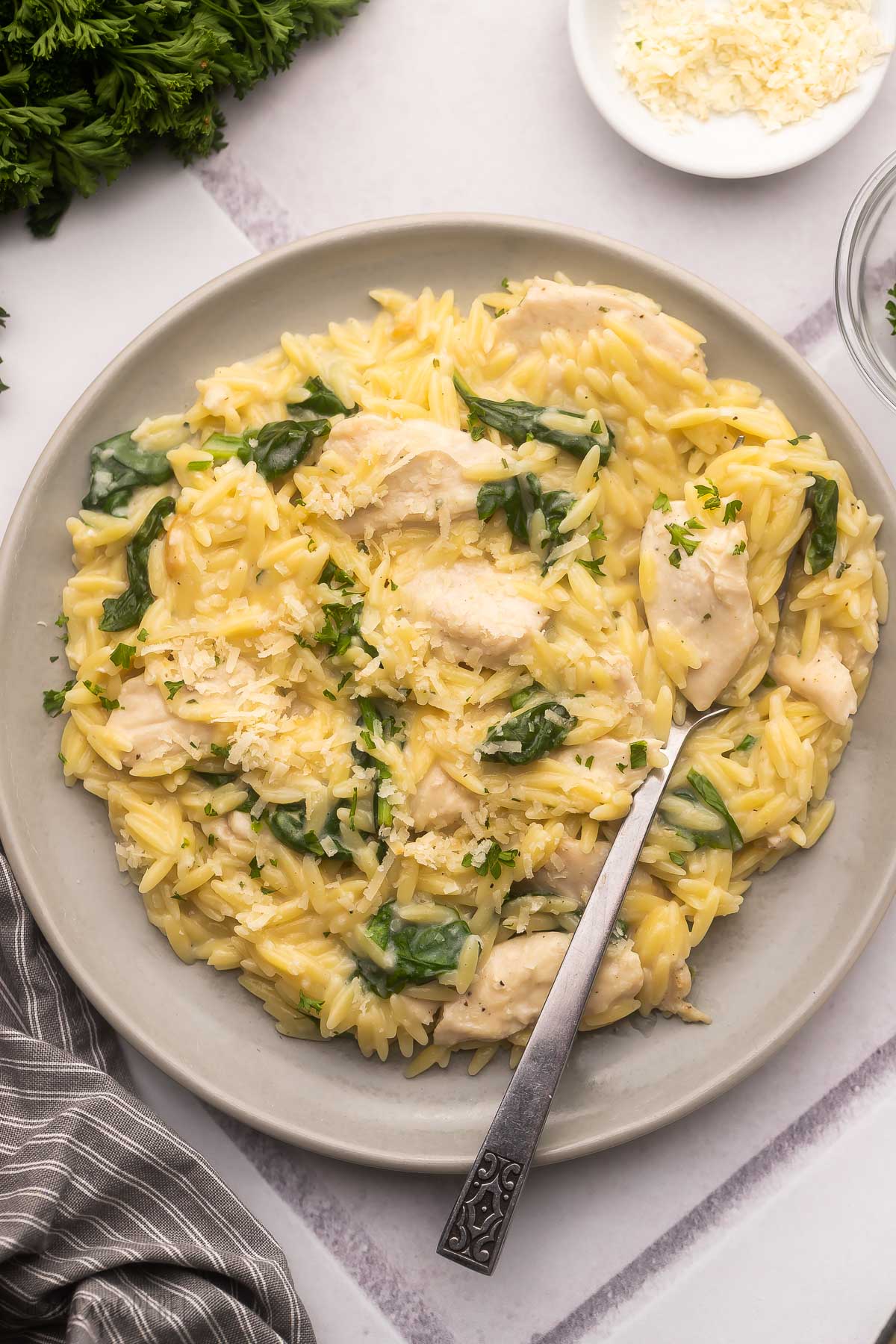 grey plate with creamy chicken orzo and a fork.