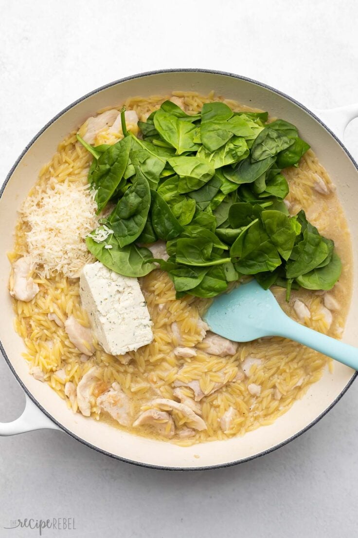 white pan with spinach and cheeses added to other ingredients.