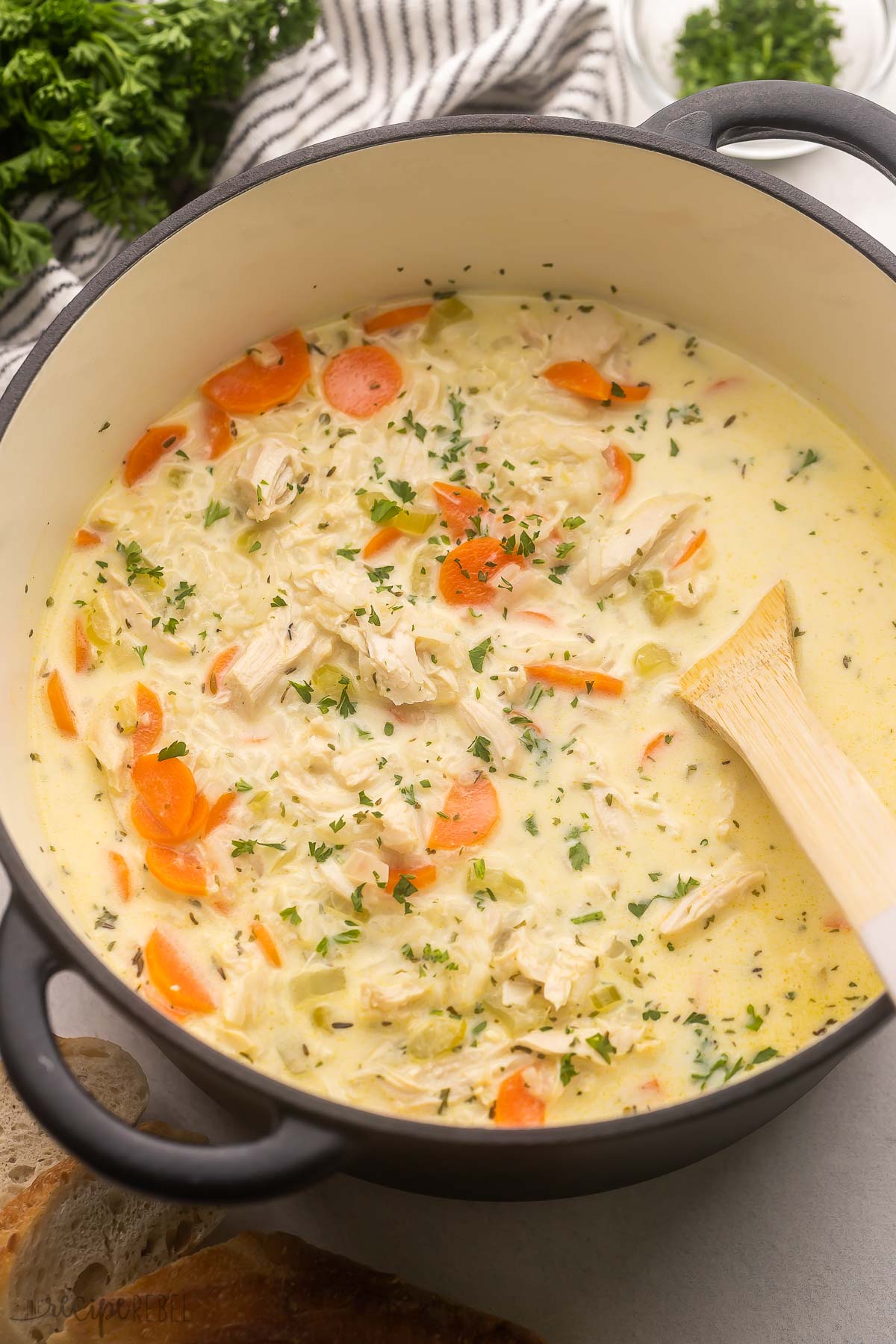 large pot with creamy chicken rice soup and wooden ladle.