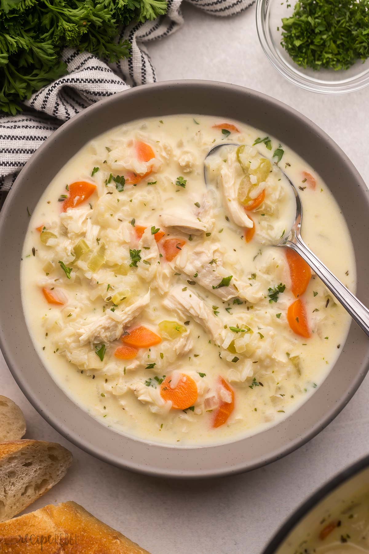 grey bowl filled with creamy chicken rice soup and spoon.