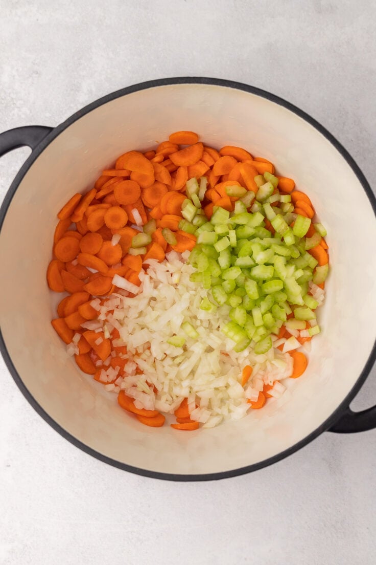 large pot with chopped vegetables on grey surface.