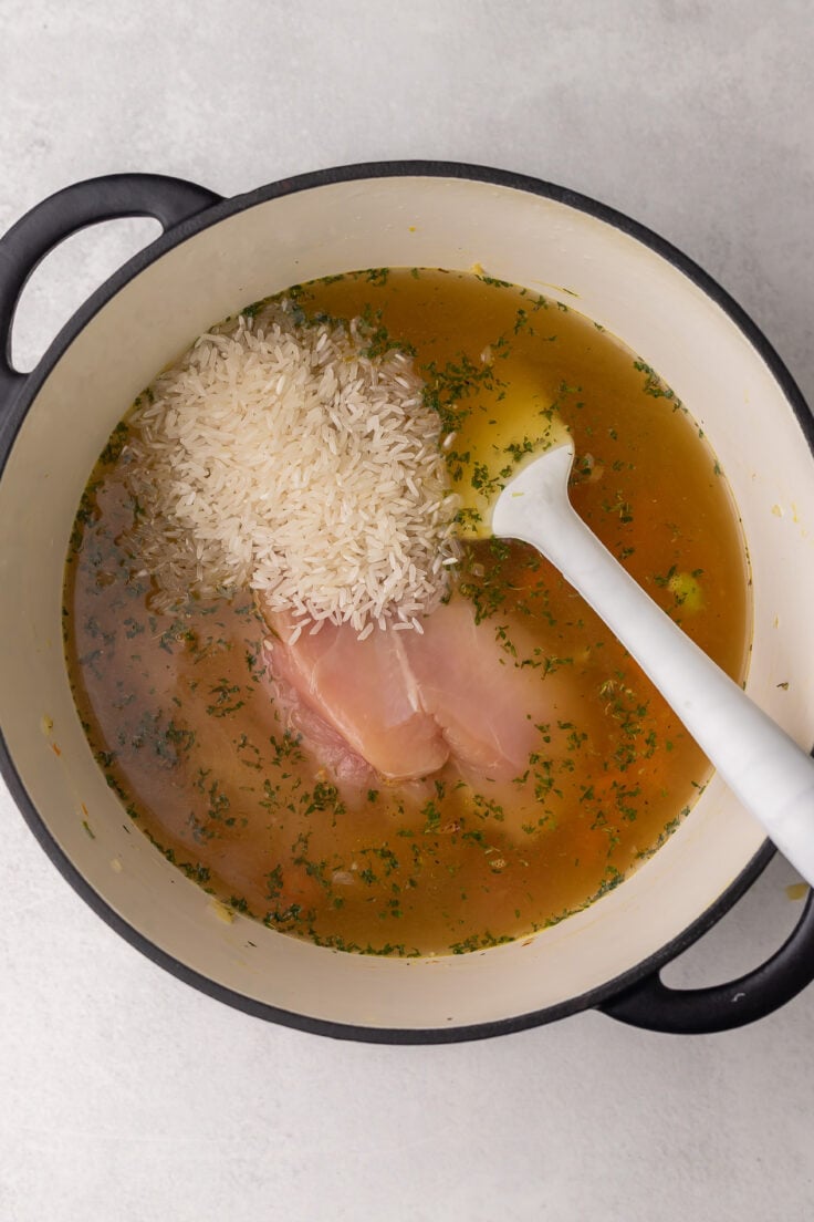 large pot with broth, chicken and rice added.