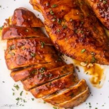 close up of a sliced chicken breast on a white plate.